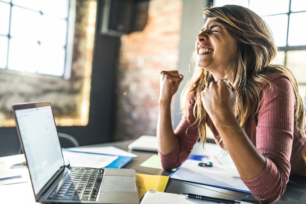 Woman at a laptop with her fist up