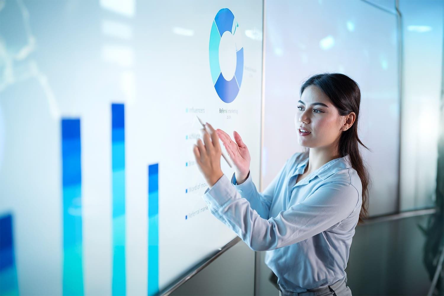 young woman presents data on large backlit screen