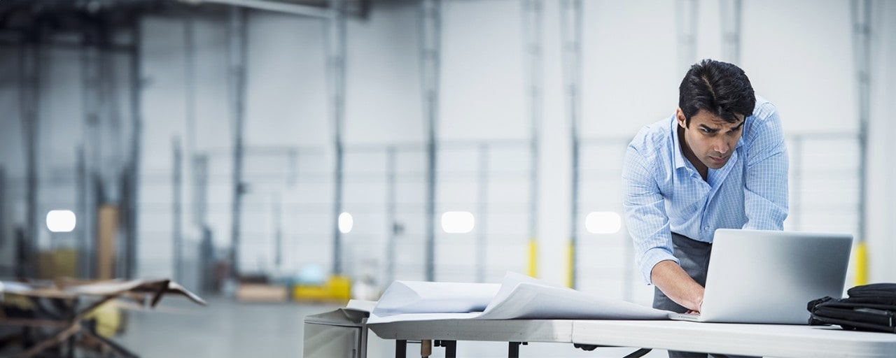 Man standing at desk working on laptop