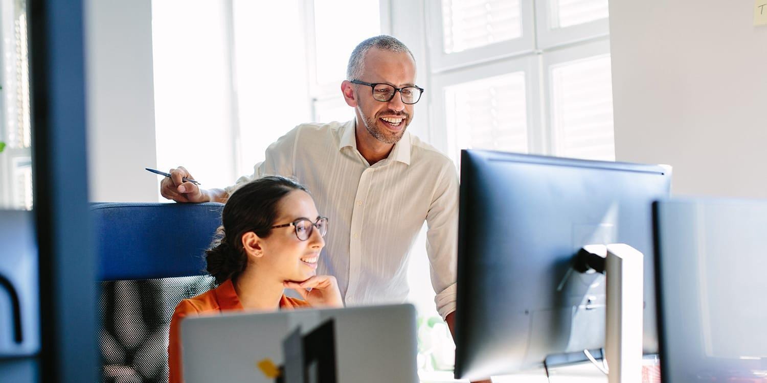 Coworkers in office setting reviewing data on computer