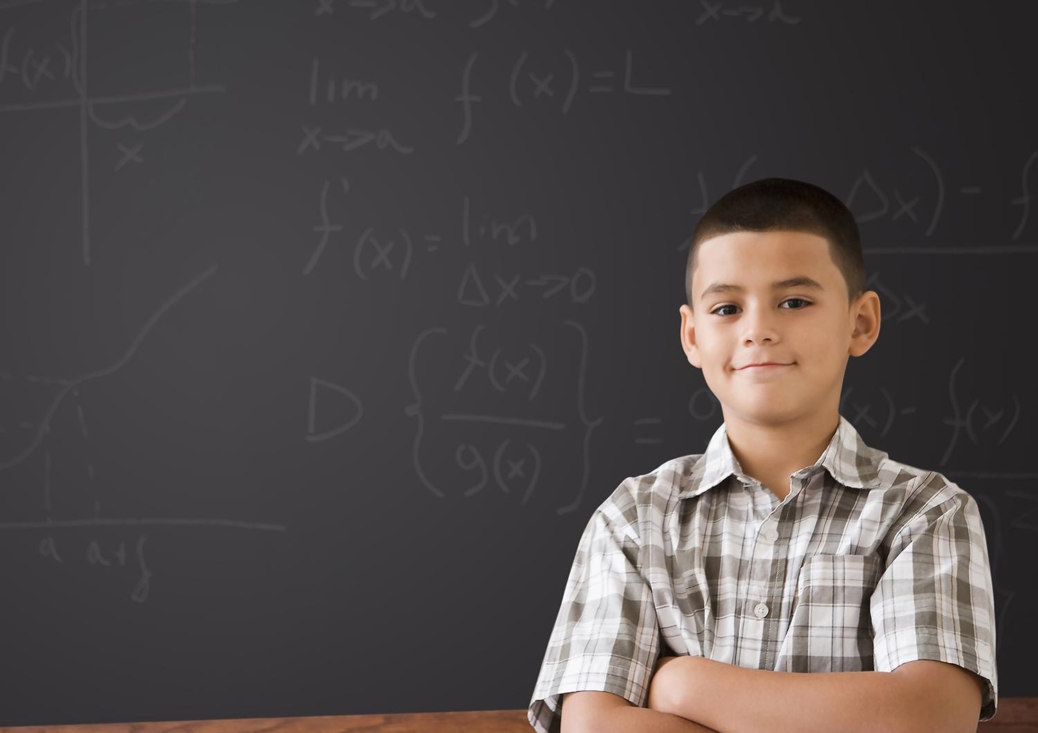 Young boy standing in front of chalkboard