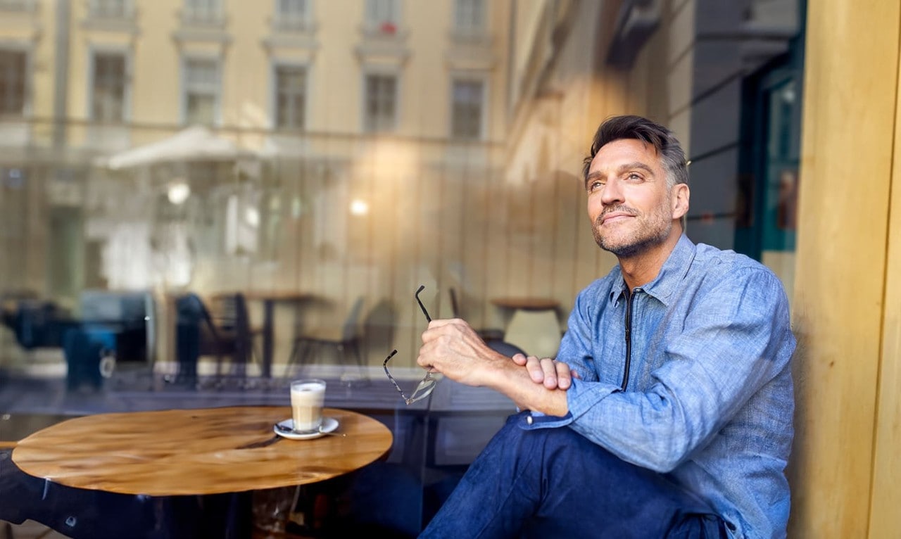 Man holding glasses and looking upward