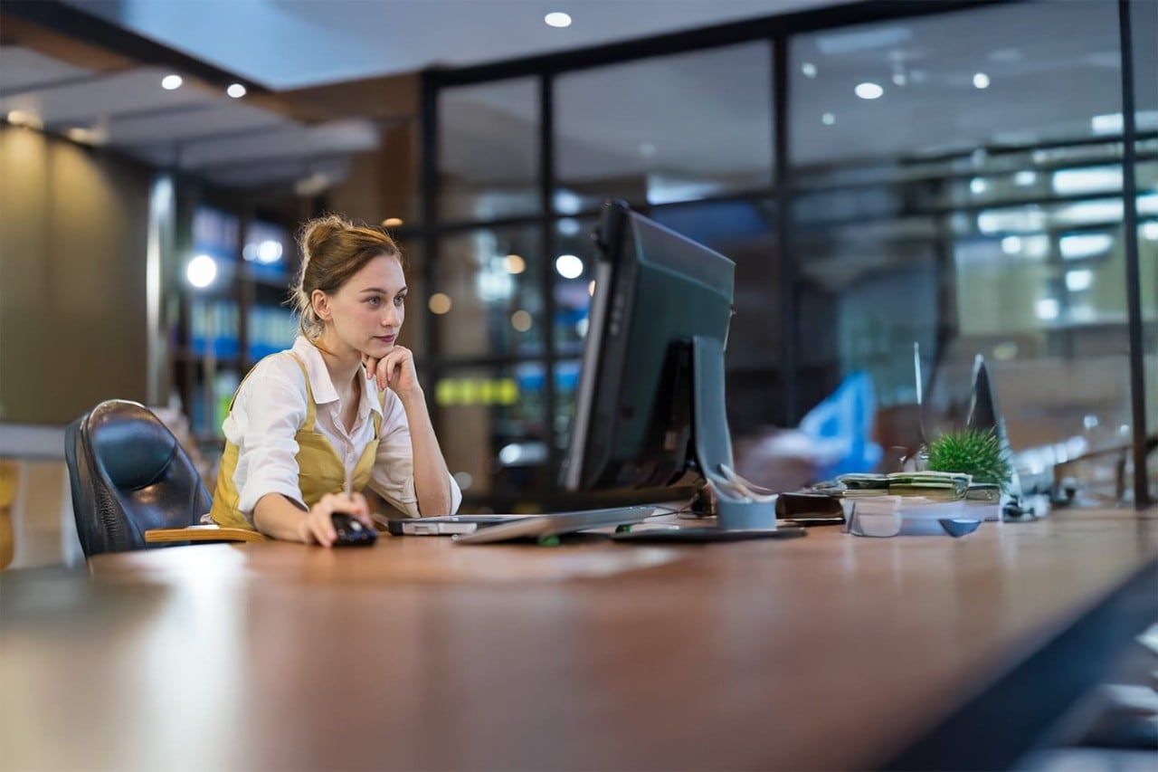 Businesswoman working on a laptop at a conference table in an office with windows