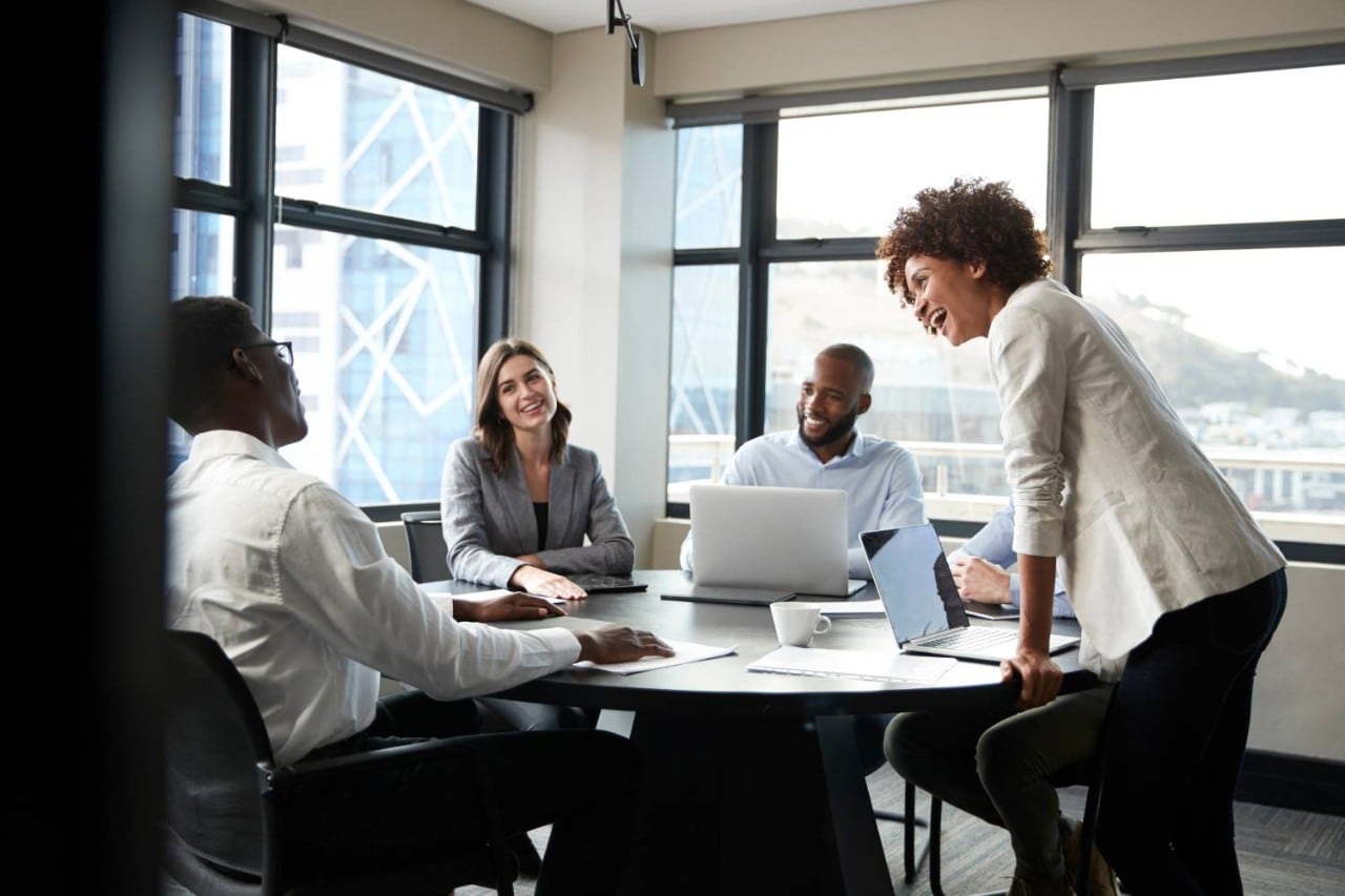 Millennial black businesswoman stands listening to corporate colleagues at a meeting, close up