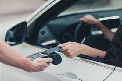 Customer using tap-to-pay on credit card terminal at drive-thru