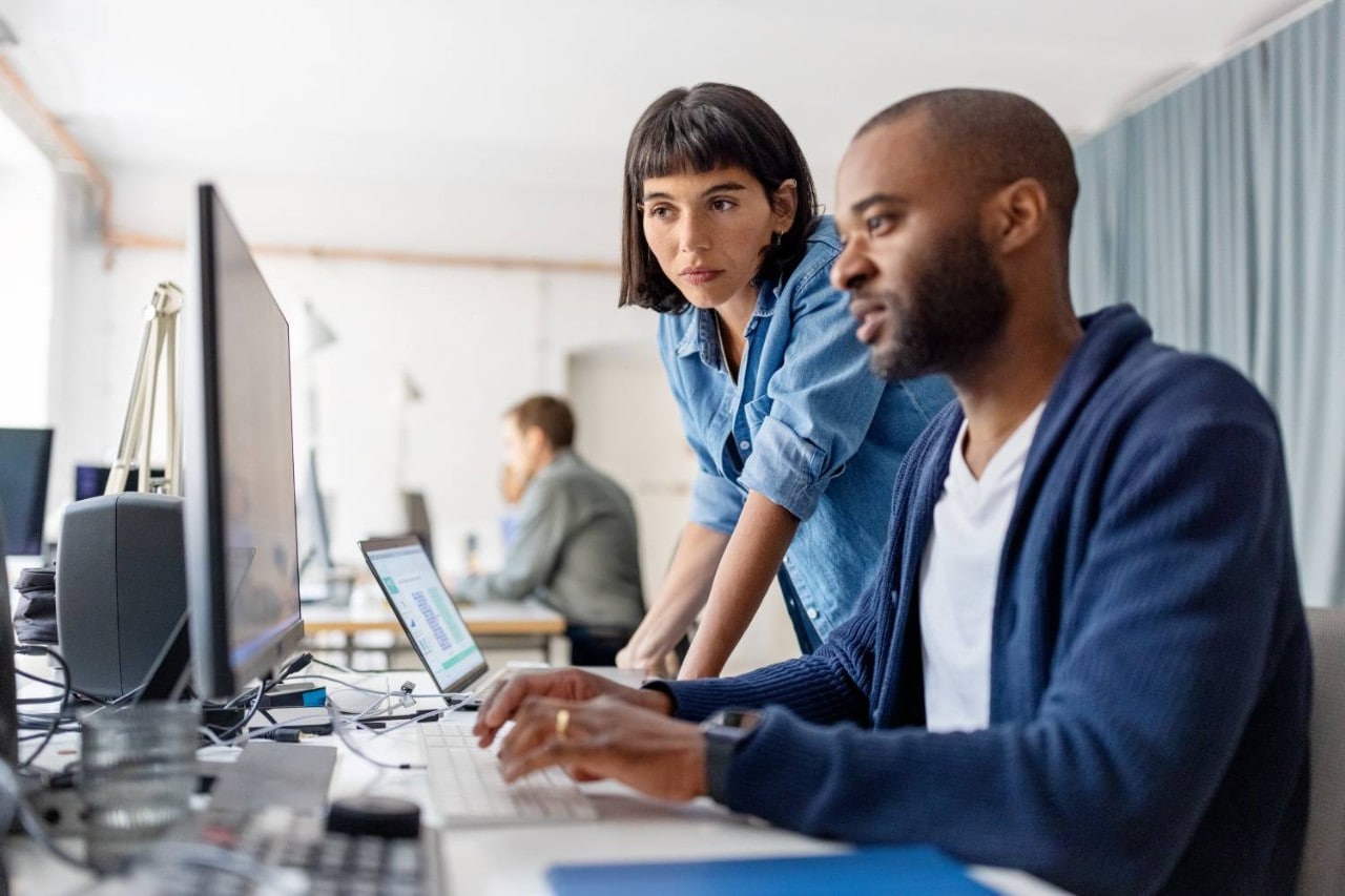 Two coworkers looking at a computer monitor