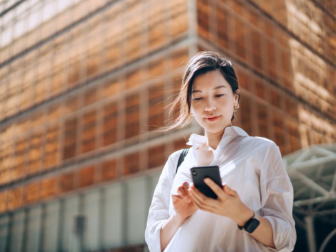 Woman standing in the city and looking at her smartphone