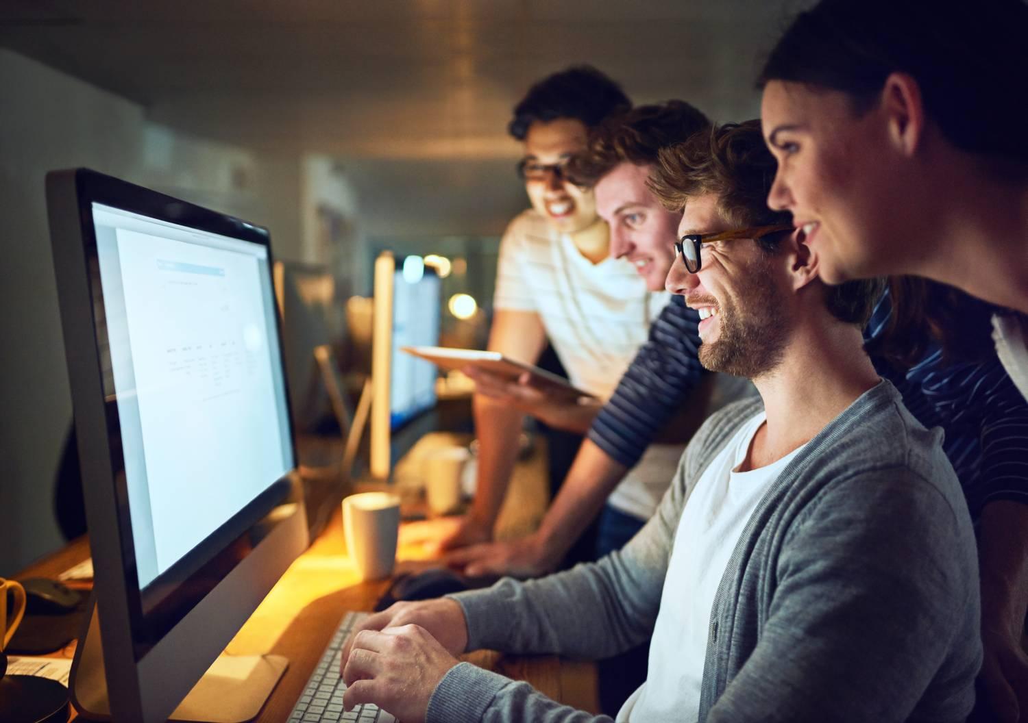 Group of coworkers reviewing work on a computer monitor