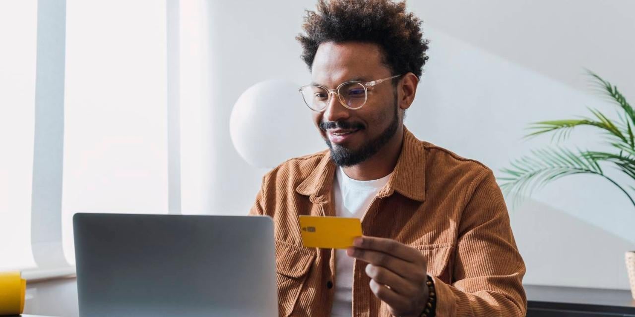 Smiling man using credit card at laptop