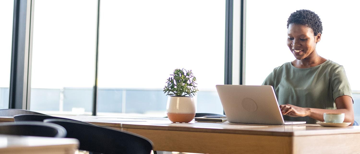 Woman at desk by a window using laptop