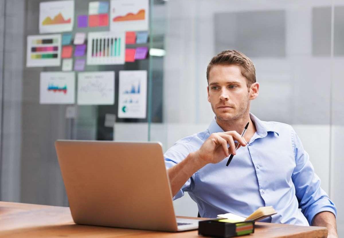 If there's a problem, he'll solve it -- shot of a young businessman working on a laptop in an office  