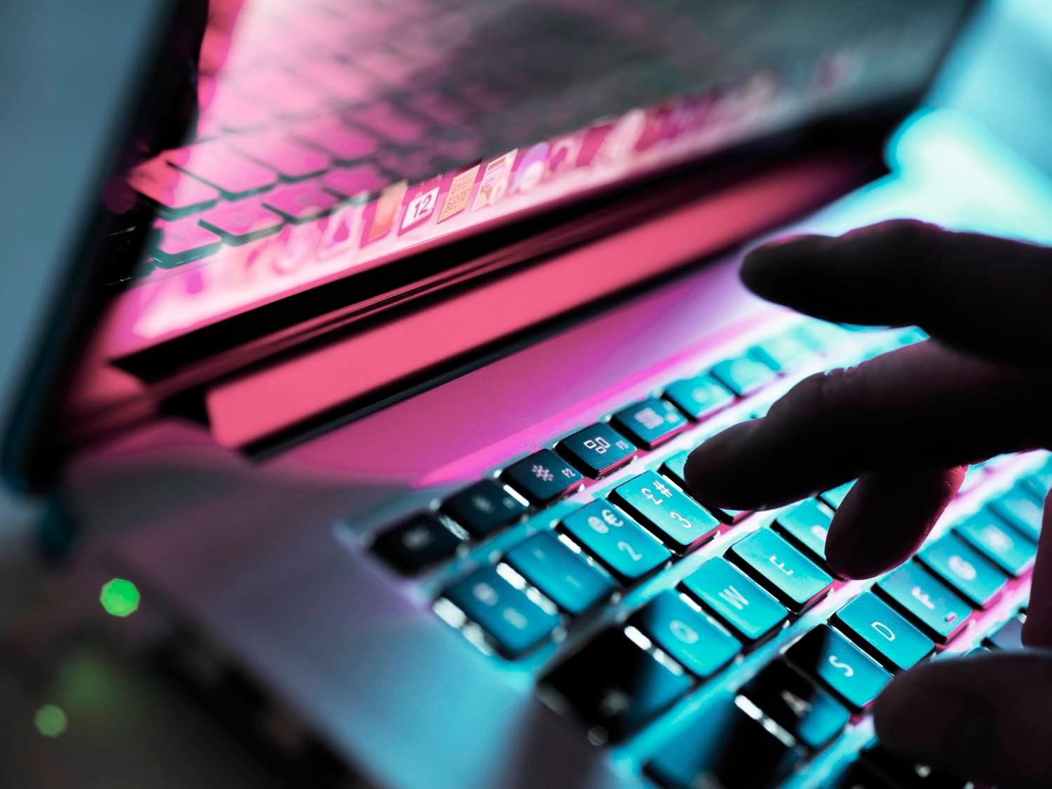 Fingers illuminated over a laptop keyboard