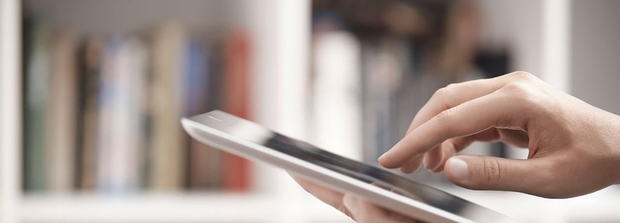 Hands holding digital tablet in library 