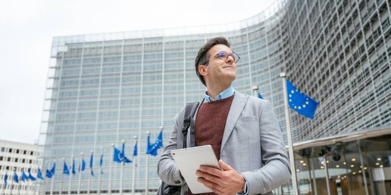 Businessman walking outside building with European Union flags