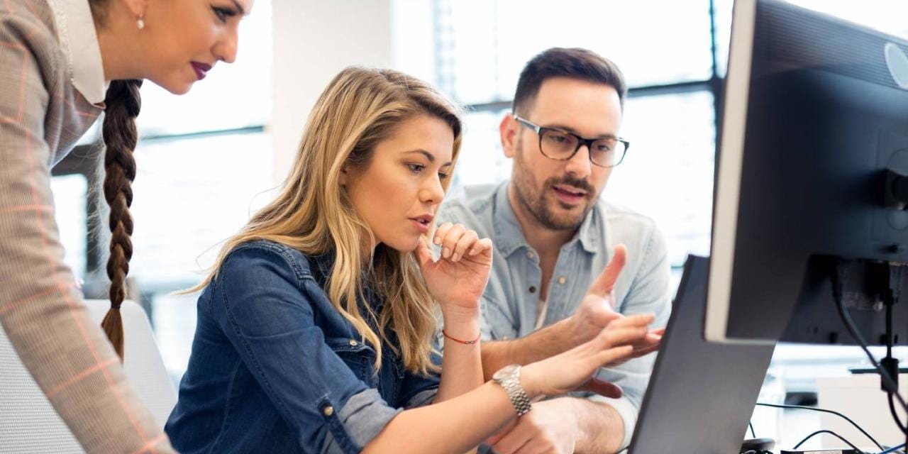 Three colleagues in open office with laptop