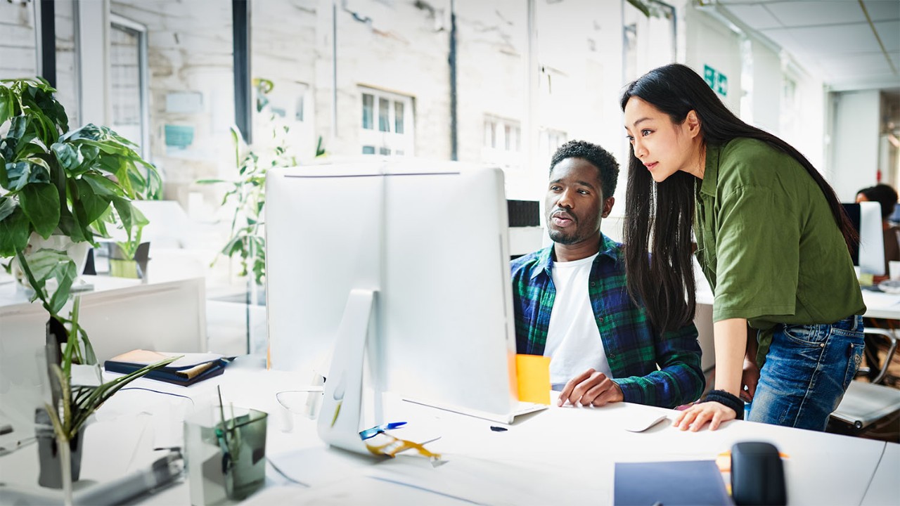 Two young business people work at computer