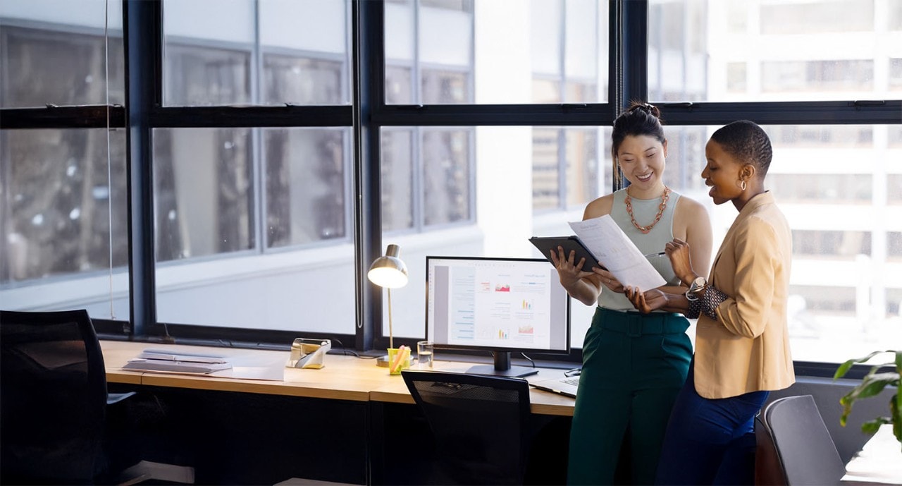 Two businesswomen pointing at a document and discussing analytics