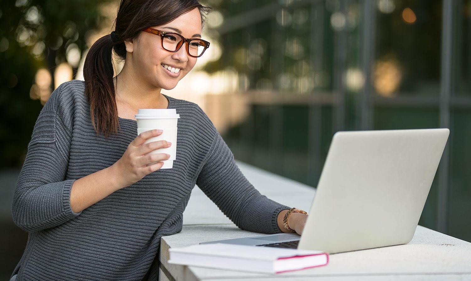 Lady outside on laptop with coffee