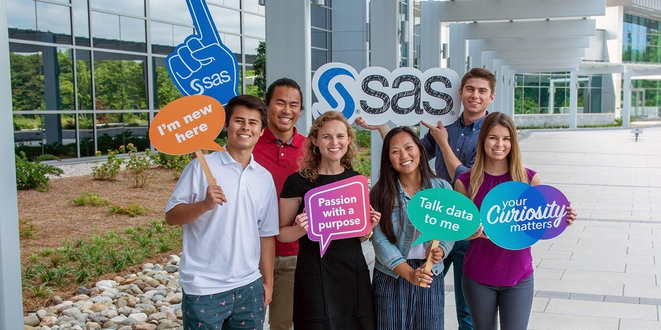 Group of young SAS employees smiling holding signs